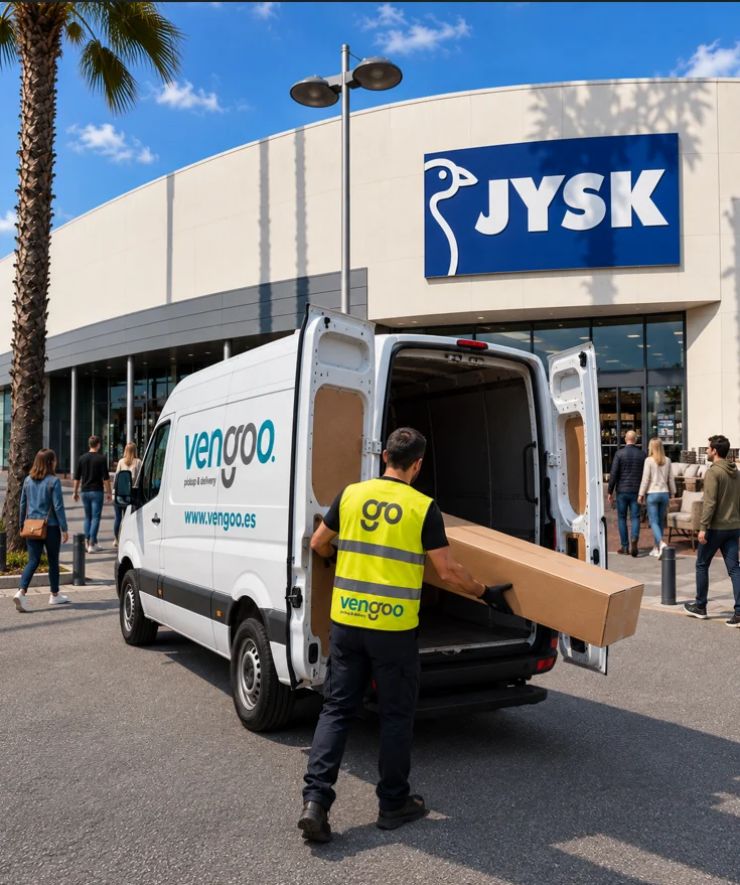 Recogida de muebles en JYSK Barcelona – Vengoo Transportista de Vengoo cargando un paquete voluminoso en una furgoneta de reparto frente a una tienda JYSK.